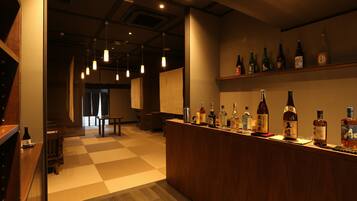 A bar area with a checkered floor, wooden counter, and various bottles.