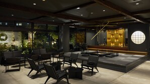 A modern interior with a seating area, a bar, and a view of greenery outside. - OYADOKOTOBUKI (Shinonsen)