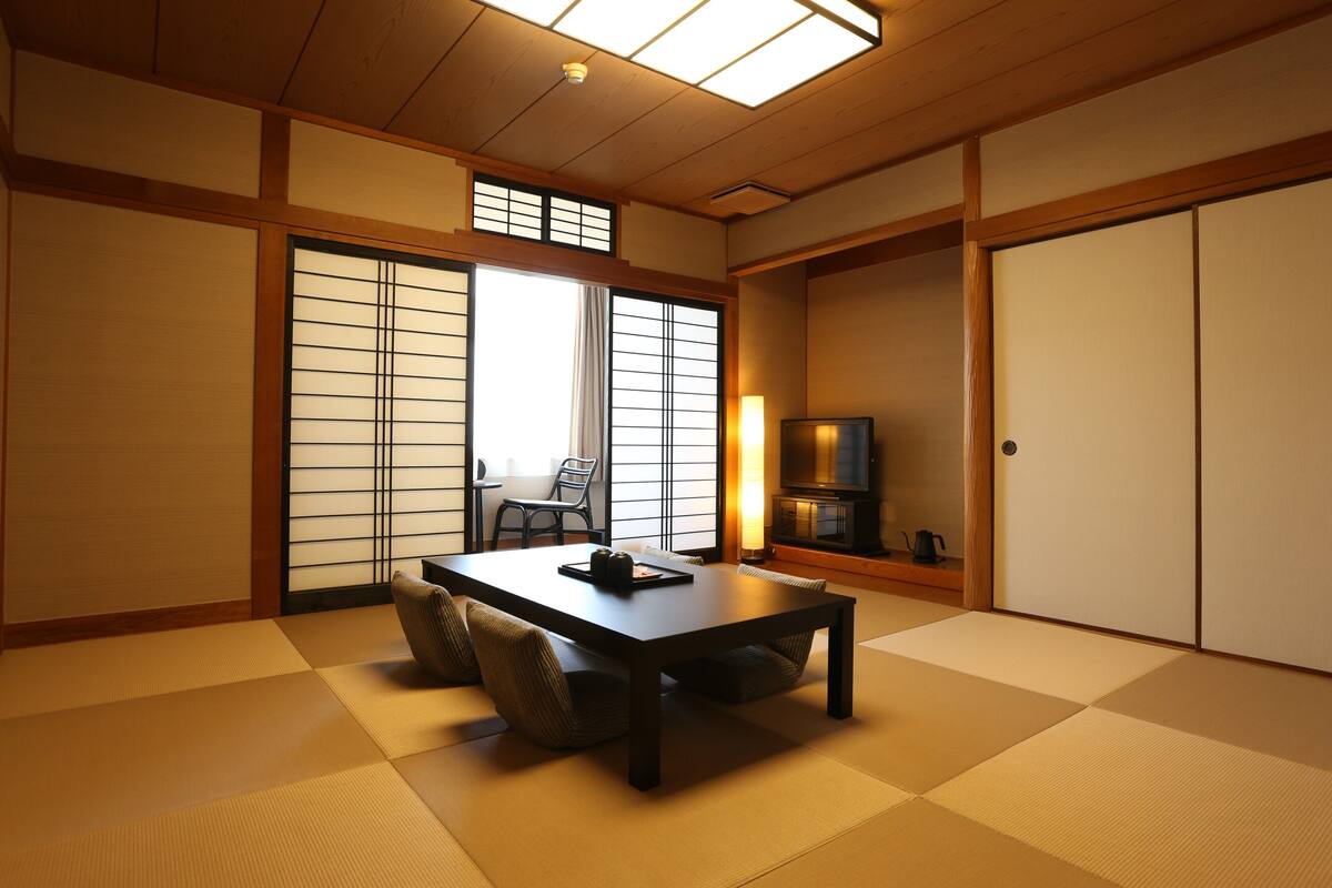 A traditional Japanese room with tatami flooring, a low table, and sliding doors.