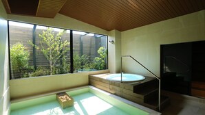 A modern bathroom with a glass-enclosed hot tub, wooden flooring, and a view of greenery outside. - OYADOKOTOBUKI (Shinonsen)