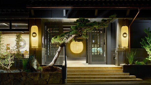 A traditional Japanese building with a stone staircase leading to a wooden door with a circular window. - OYADOKOTOBUKI (Shinonsen)