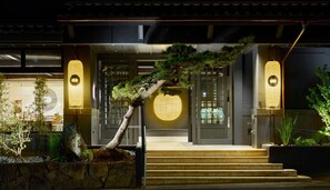 Un edificio japonés tradicional con una escalera de piedra que lleva a una puerta de madera con un ventanal circular.