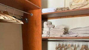 A closet with wooden shelves and hangers, containing folded towels and clothes. - Appartement en Duplex Centre Historique (Montpellier)