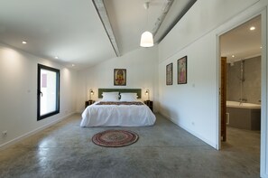 Un dormitorio con una cama grande, lámparas de noche, un tapete redondo y un cuadro en la pared.