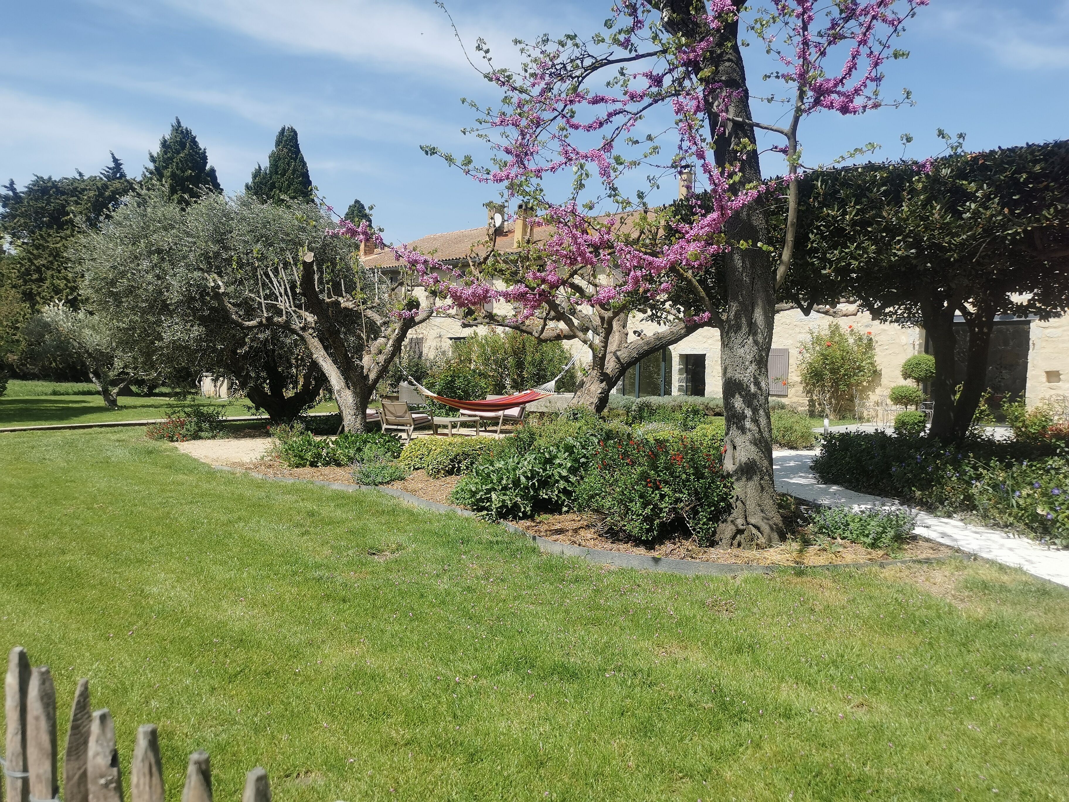 A garden with a hammock, a stone building, and a clear sky.