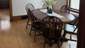 Una sala da pranzo con tavolo in legno, sedie, un lampadario, quadri incorniciati e vista dalla finestra.