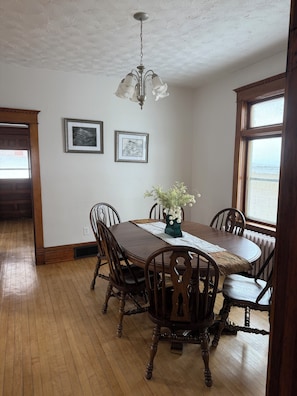 A dining room with a wooden table, chairs, a chandelier, framed pictures, and a view through a window. - Downtown-Adjacent Historic Home / Modern Updates (Marquette)