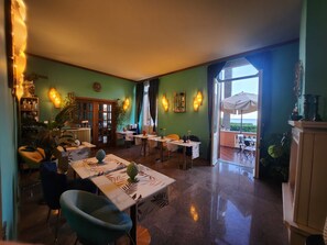 Uma área de refeições com mesas, cadeiras e vista para o exterior.