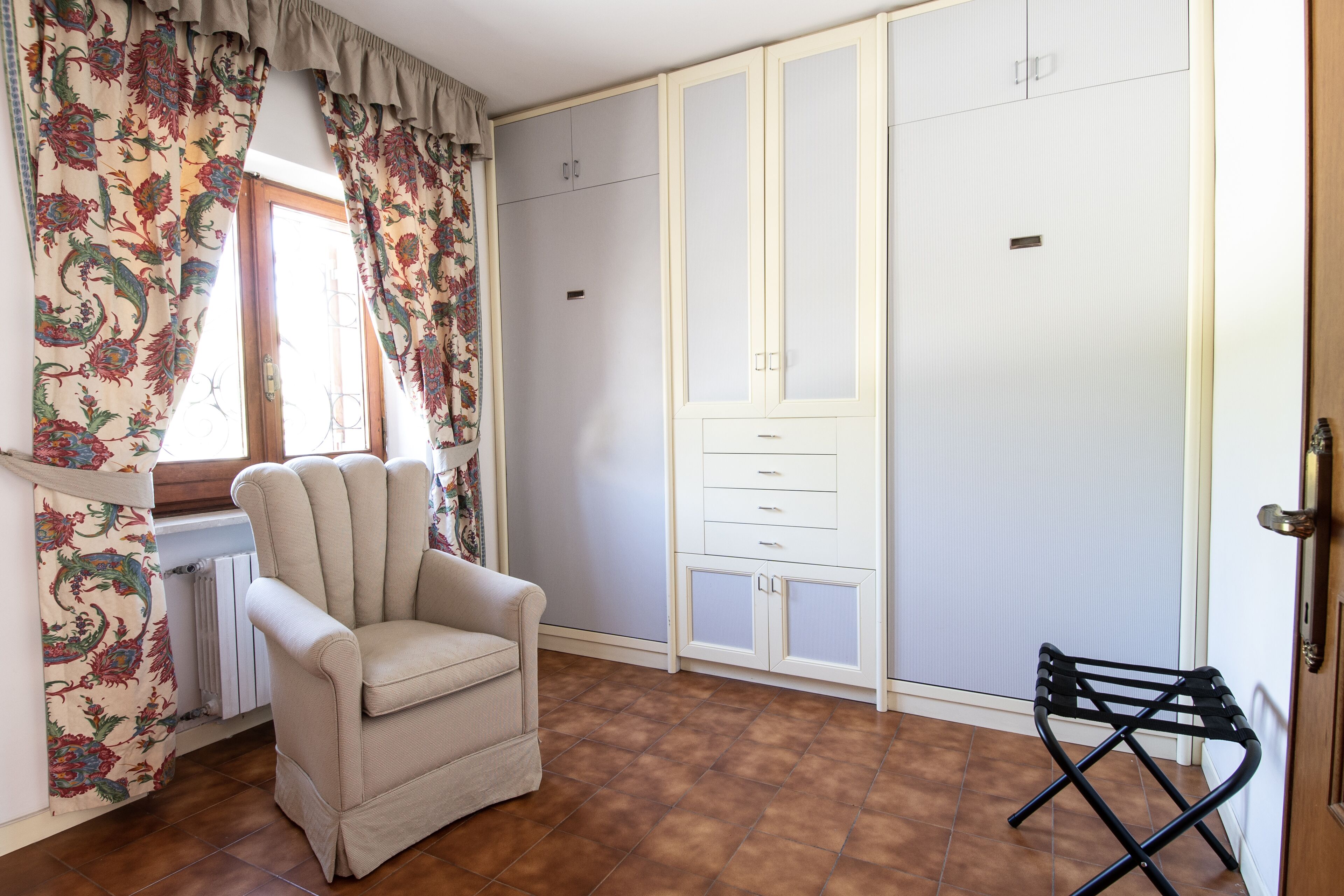 A room with a chair, a wardrobe, and a radiator.