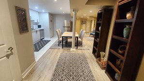A modern kitchen with white cabinets, a stainless steel refrigerator, and a dining area with a table and chairs.