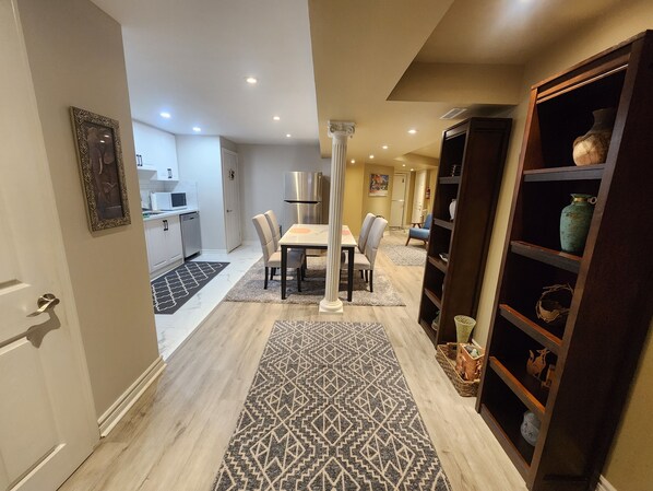 Una cocina moderna con armarios blancos, un refrigerador de acero inoxidable y una zona de comedor con mesa y sillas.