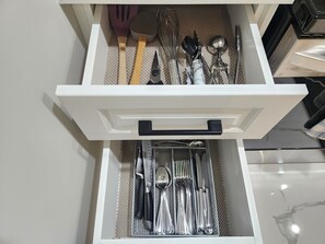 A drawer with neatly organized kitchen utensils including spoons, forks, and knives.