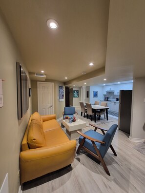 Un salon moderne comprenant un canapé, des fauteuils, une table basse et un coin repas avec une table et des chaises.