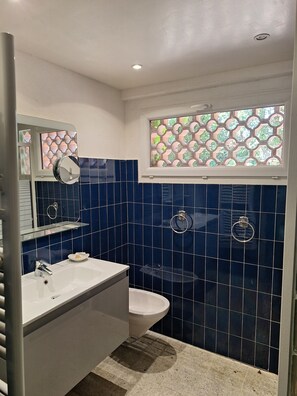 Ein Badezimmer mit einem weißen Waschbecken, einer Toilette und einem Spiegel.