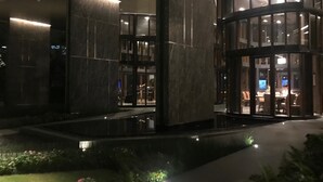 A modern building with a glass entrance, a water feature in front, and a well-lit interior. - Excellent location, best facilities ,worth to pay (Jatujak)