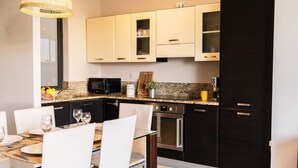 Une cuisine moderne avec des armoires blanches, un comptoir en granit et des appareils électroménagers en acier inoxydable.