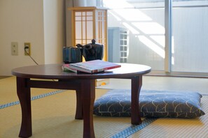 A tatami mat room with a low wooden table, a cushion, and a traditional Japanese tea set.