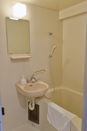 A bathroom with a sink, mirror, and shower.