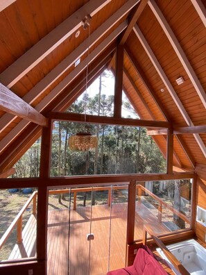 Una terraza de madera con un jacuzzi y vistas a un bosque.