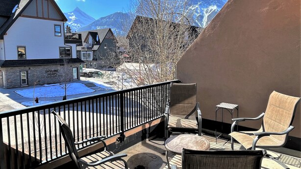 Ein Balkon mit Gartenmöbeln, Blick auf verschneite Landschaft und einen Berg im Hintergrund.