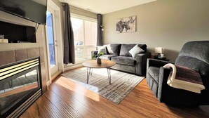 Ein Wohnzimmer mit Kamin, einer Sofagarnitur, einem Couchtisch und einem Gemälde an der Wand.