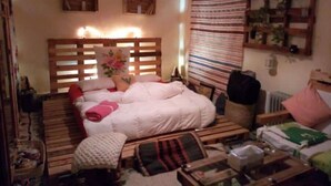 A cozy bedroom with a wooden bed, a small table, and a hanging light fixture. - Atlas room (w) (Agadir)
