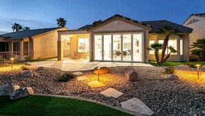 Una casa moderna con un patio, ventanas amplias y una entrada bien iluminada.