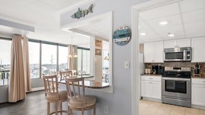Una cocina moderna con armarios blancos, electrodomésticos de acero inoxidable y vistas a la ciudad a través de amplios ventanales.