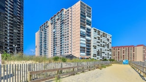 Un hotel frente a la playa con varios edificios altos, una playa de arena y una pasarela de madera.