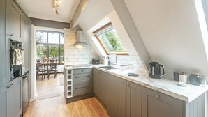A modern kitchen with grey cabinets, a wooden floor, and a skylight. - 1 bedroom accommodation in Burraton, near Ivybridge (Burraton, near Ivybridge)