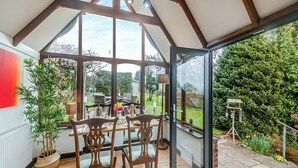 A conservatory with a dining table and chairs, large windows, and a view of a garden. - 1 bedroom accommodation in Burraton, near Ivybridge (Burraton, near Ivybridge)