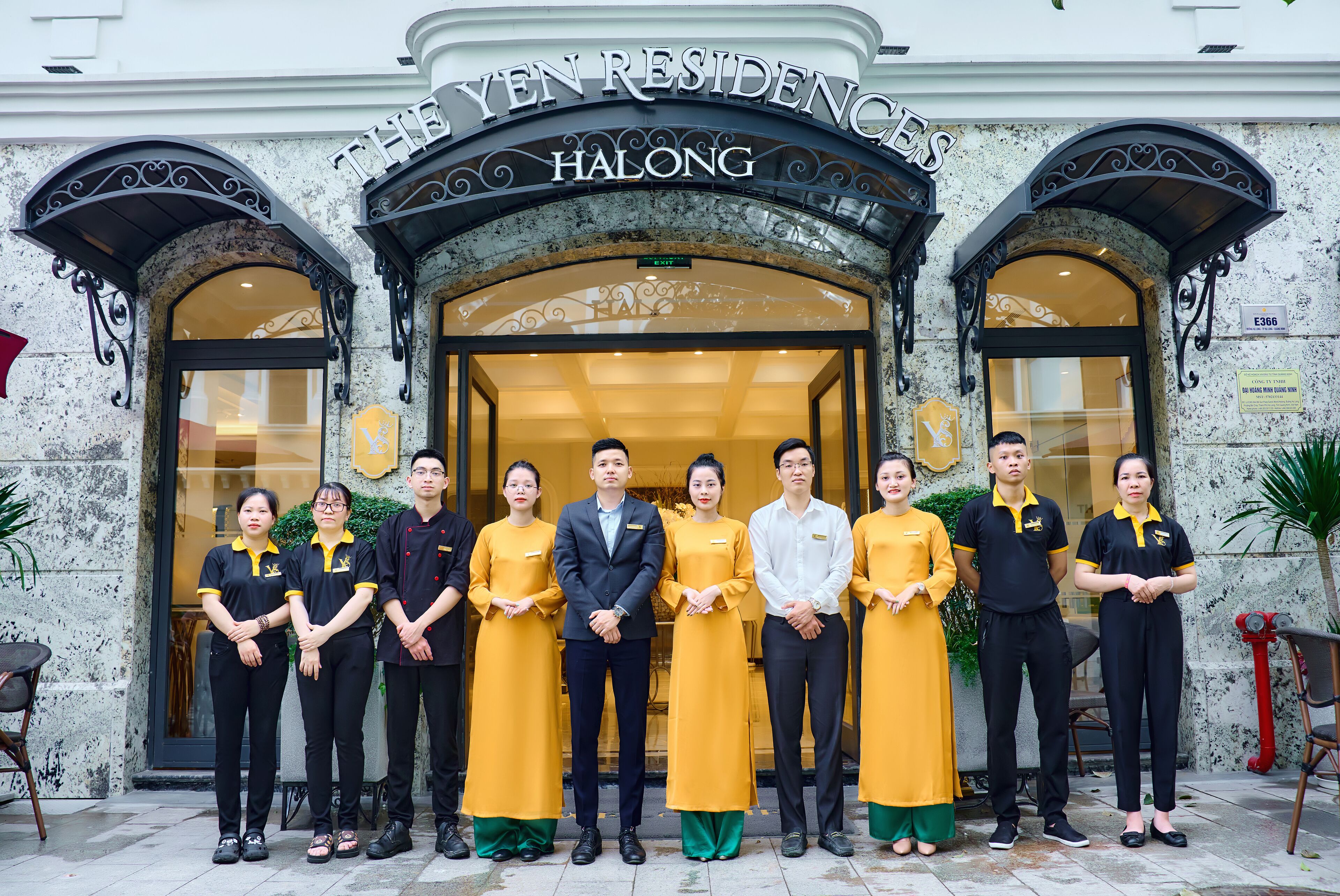 A group of people standing in front of a building with a sign that reads "THE YEN RESIDENCES HALONG".
