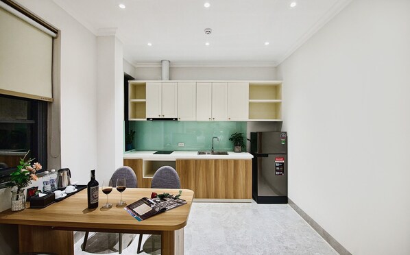 A compact kitchen with white cabinets, a green backsplash, and a black refrigerator.