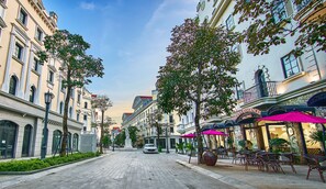 A street lined with historic buildings, a parked car, and outdoor seating with umbrellas.