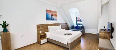 Una habitación de hotel moderna con una cama grande, un escritorio, una silla y un televisor.