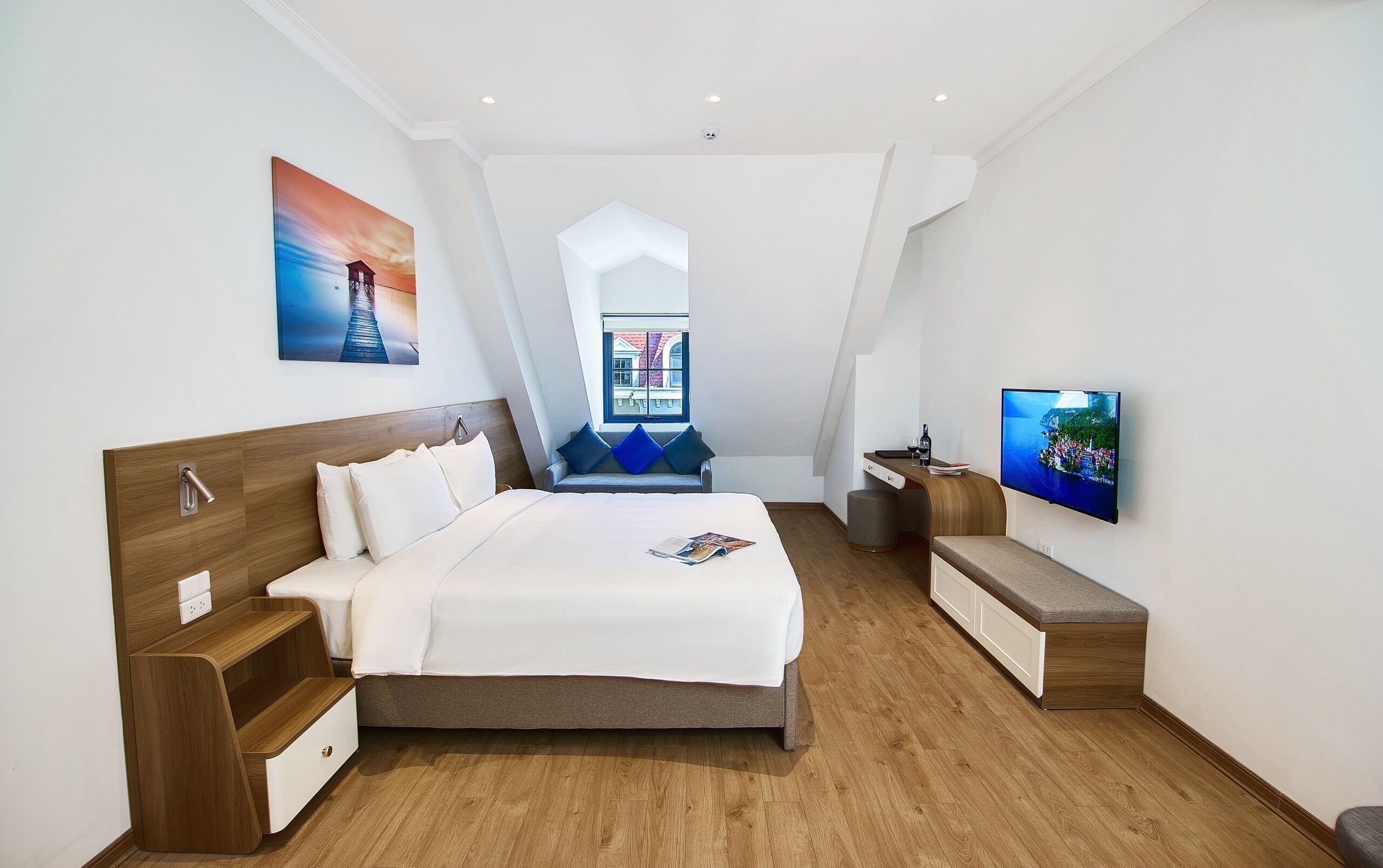 Habitación de hotel moderna con una cama grande, televisión, escritorio y ventana con vista a la ciudad.