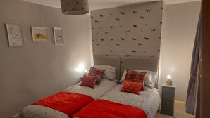 Een slaapkamer met een bed, twee nachtkastjes en een hoofdbord met een hondjesprint.