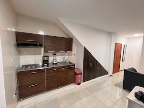 A compact kitchen with a gas stove, a coffee maker, and a trash bin. - Apartamento Casa del Bosque (Cali)