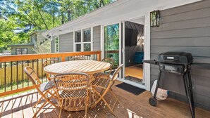 A deck with a round table and wicker chairs, a grill, and a sliding glass door leading to a covered patio. - Modern, Cozy Buckhead 4+3 SFH + Backyard (Atlanta)