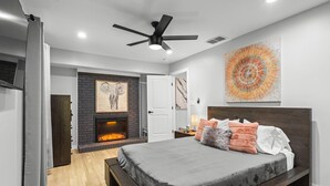 A modern bedroom with a large bed, a fireplace, and a ceiling fan. - Modern, Cozy Buckhead 4+3 SFH + Backyard (Atlanta)