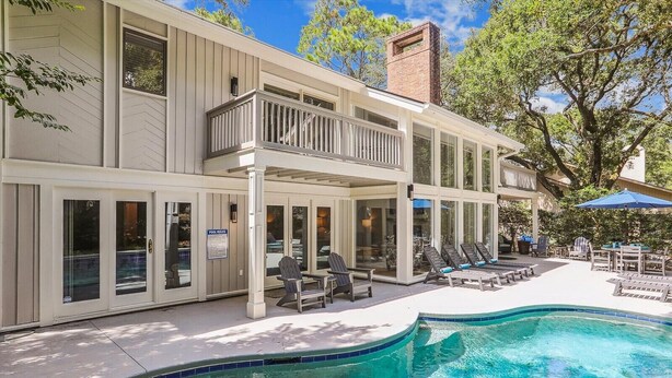 A modern building with a swimming pool, outdoor seating, and a covered patio area.