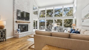 A modern living room with a fireplace, large windows, and a view of the outdoors.