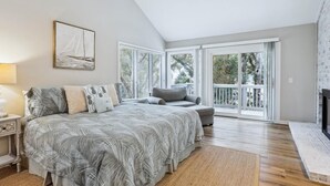 A spacious bedroom with a large bed, a sofa, and a ceiling fan.