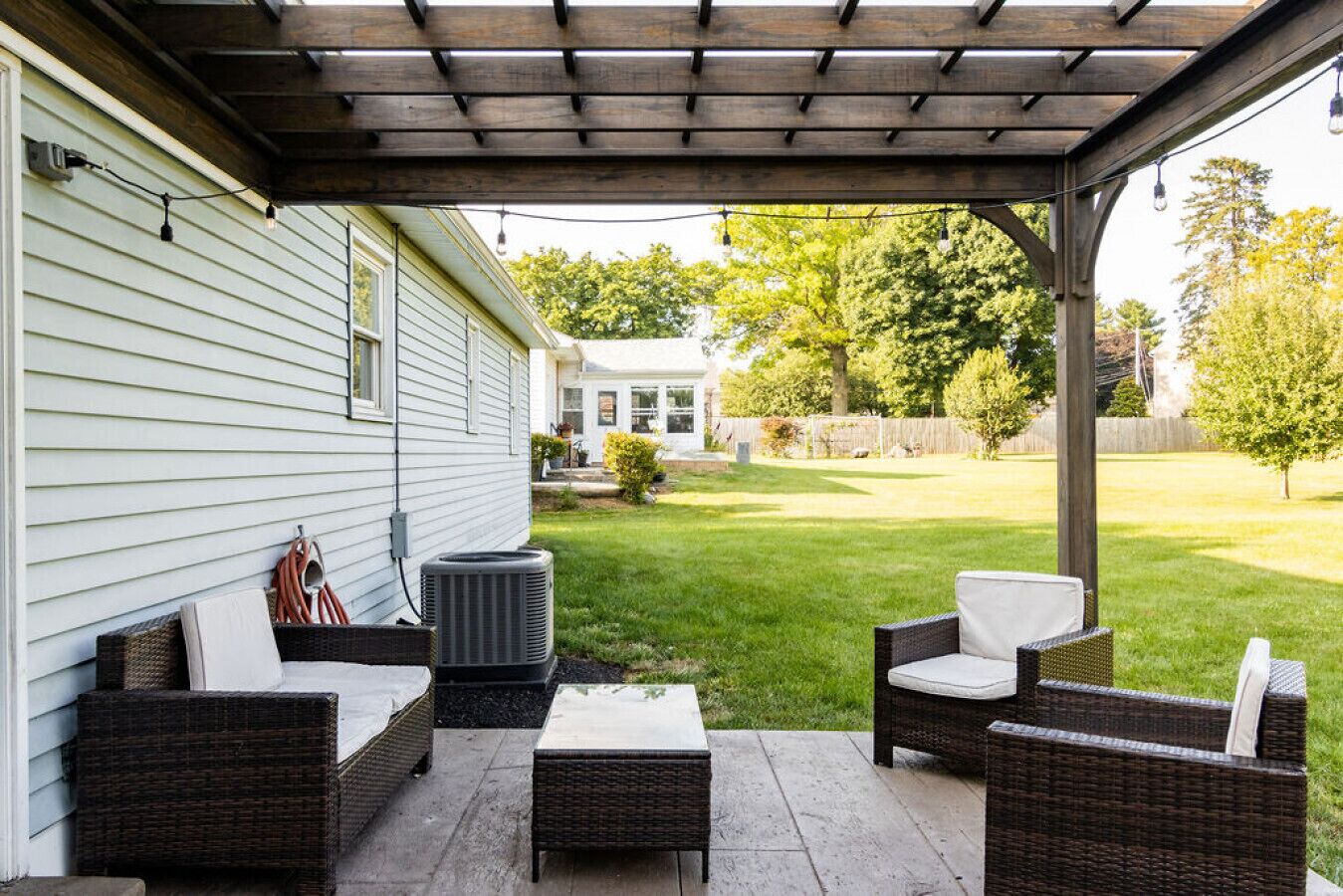 Covered patio w/ cushioned seating, perfect for relaxing while overlooking the spacious backyard.