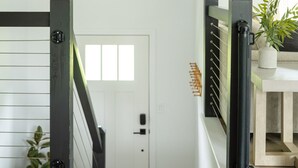 A staircase with a black railing, a white door, and a hanging light fixture.