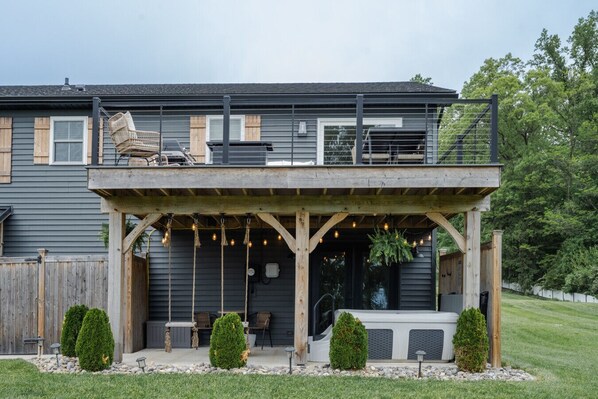 A two-story house with a covered patio area featuring outdoor seating and string lights.