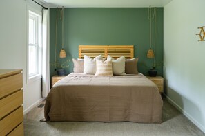 A bedroom with a bed, bedside tables, a window, and a green wall.