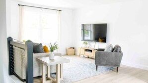 A modern living room with a sofa, a small table, a TV mounted on the wall, and a radiator.