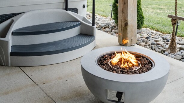 A covered outdoor area with a hot tub, a fire pit, and string lights.