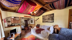 Ein gemütliches Wohnzimmer mit einer Couch, einem Esstisch und einem durch einen Bogen sichtbaren Küchenbereich.